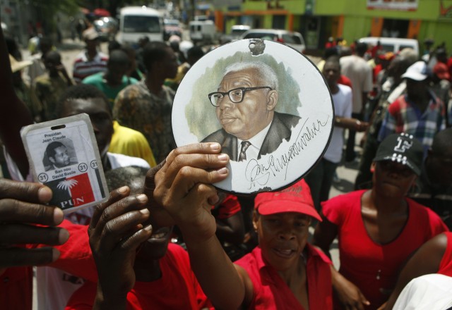 Haitiere er splittet når det kommer til Duvalier. Her demonstrerer støttespillerne til Papa Doc (bilde på tallerken) for at hans sønn Baby Doc (på plakaten bak) skal få komme tilbake til landet. (AP Photo/Esteban Felix)