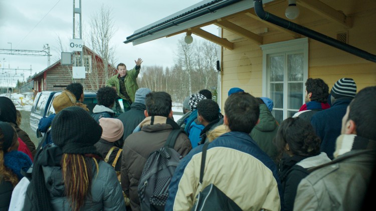 Per Primus (Anders Baasmo Christiansen) tar i mot asylsøkerne på togstasjonen i Welcome to Norway! (Foto: Motlys / Norsk Filmdistribusjon).