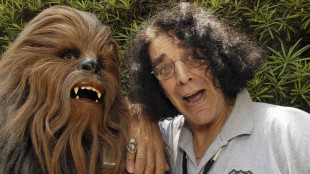 Chewbacca-skuespilleren Peter Mayhew ved siden av drakten som gjorde ham berømt i 2005. (Foto: AP Photo/Disney, Mark Ashman)