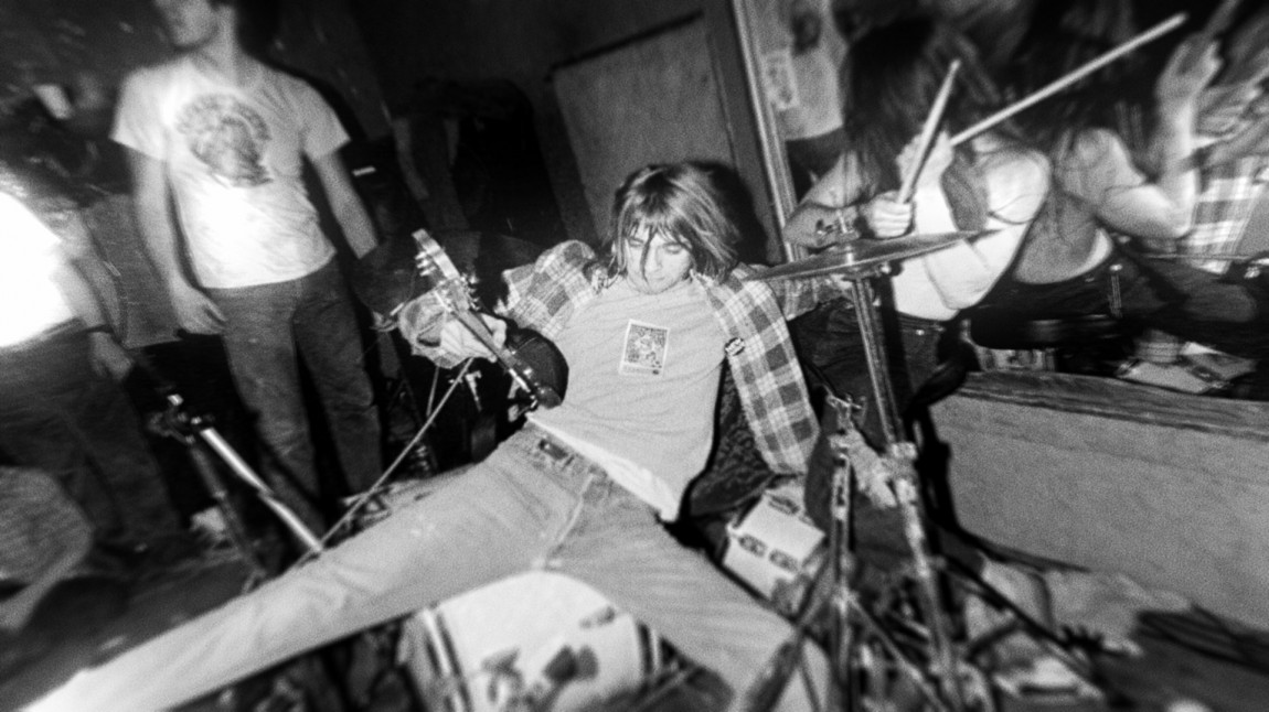 Kurt Cobain sittende på et trommesett under en av Nirvanas tidlige konserter. (Foto: Arts Alliance, End of Movie, LLC) 
