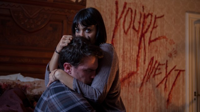 Zee (Wendy Glenn) og Felix (Nicholas Tucci) foran illevarslende grafitti i You're Next (Foto: Scanbox).