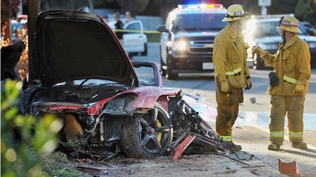 Brannmenn står ved bilvraket etter at skuespilleren Paul Walker og en venn krasjet og døde lørdag.  (AP Photo/The Santa Clarita Valley Signal, Dan Watson)