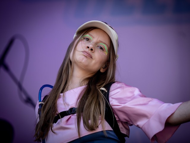 Michelle Ullestad har på seg en cammelback og en rosa caps. Hun står på en scene utendørs.