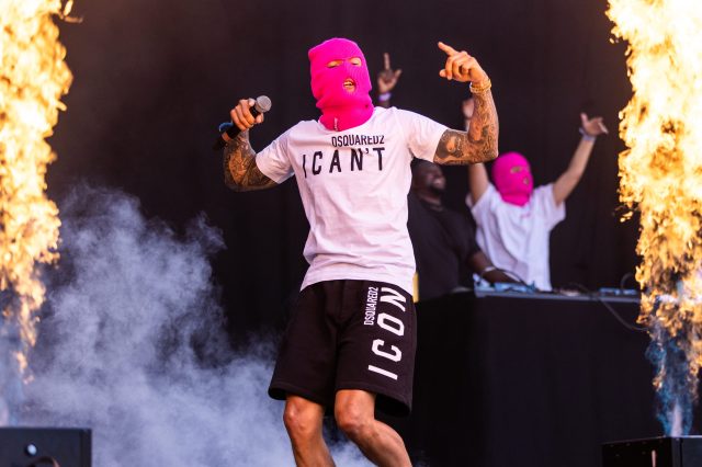 Kamelen har på seg den rosa Ballinciaga-masken. Han står på scenen sammen med medlemmer av Ballinciaga og det er flammer, det vil si pyro, rundt dem.