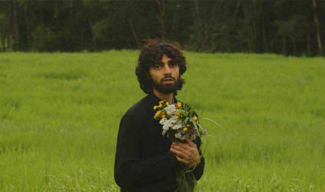 Turab står ute i en blomstereng og holder en bukett og ser sårbar ut.