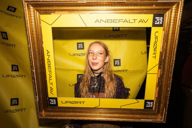Kvinne står med hodet i en bilderamme på en fest
