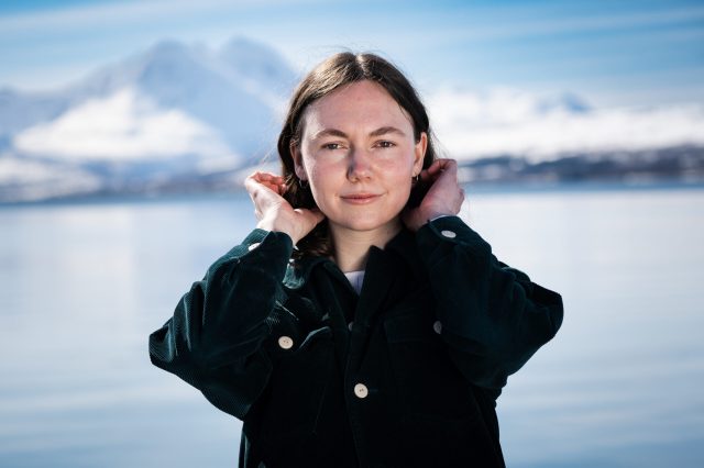 Stéphanie Turcotte sitter ved vannet i Tromsø. Hun har blå øyne og brunt hår.