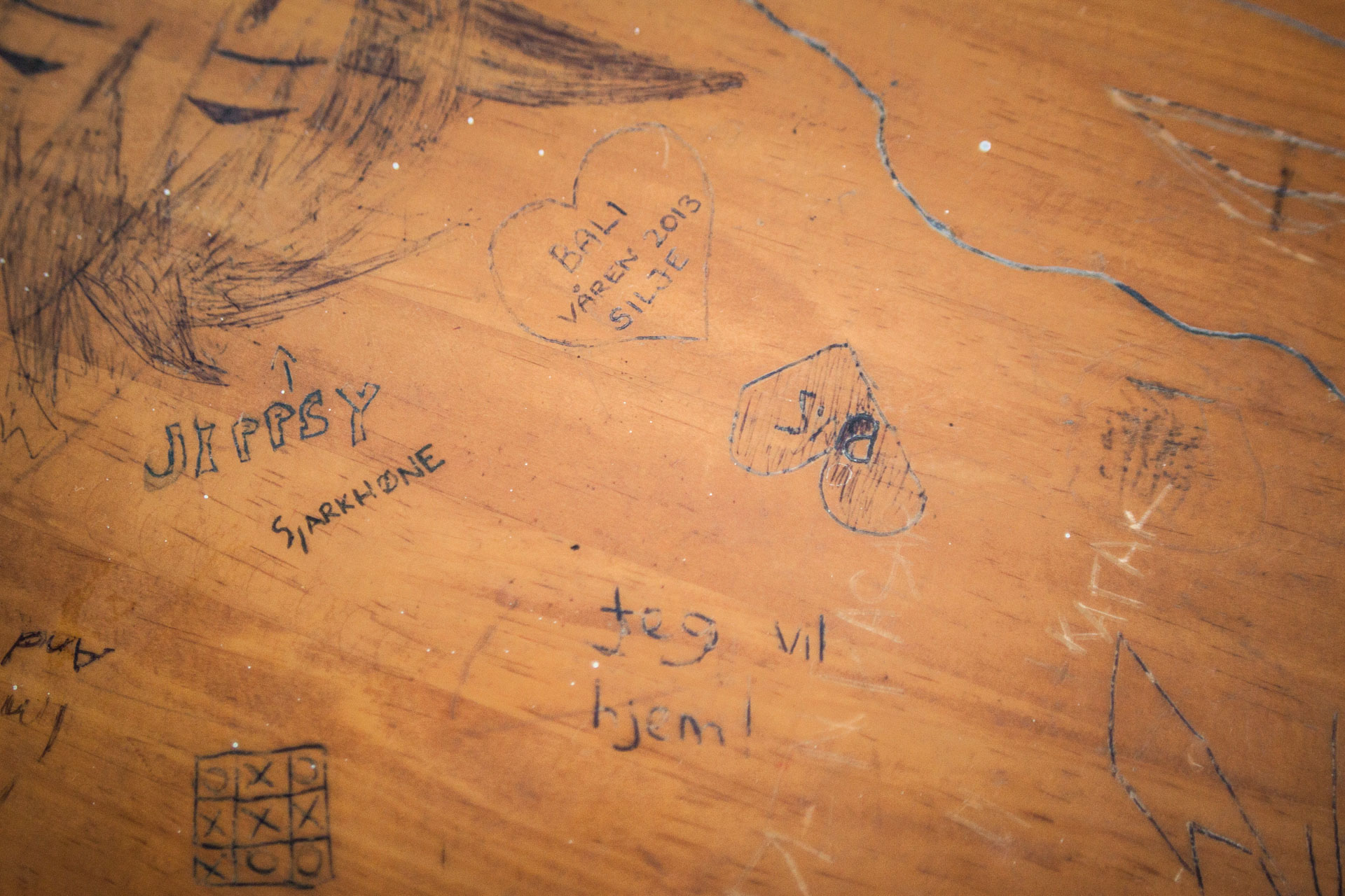 «Jeg vil hjem». Skriblerier på en av skolepultene. (Foto: Andrea A. Thiis-Evensen)