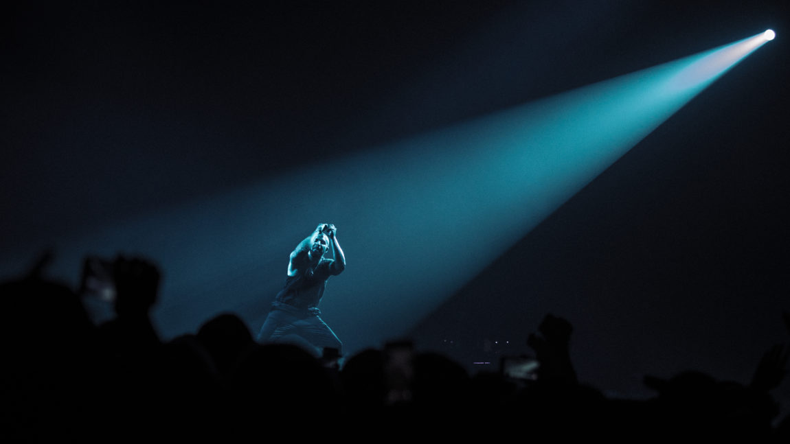 Et bilde av Drake på Telenor Arena i 2017. Drake har en spotlight på seg mens han danser. Rommet er ellers helt sort og mørkt.
