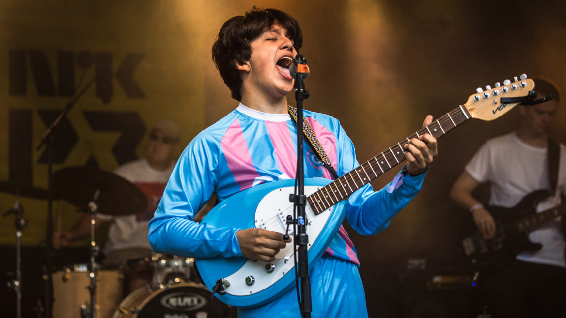 Boy Pablo står på ei scene og syng av full hals. Bak han venstre sit ein trommeslager og til høgre står ein gitarist. Boy Pablo står i framgrunnen ved eit mikrofonstativ. Han har svart, halvlangt hår. Han syng og gaper så høgt at vi ser tunga og tennene hans.  Han har på seg ei langerma fotballdrakt som er babyblå med babyrosa, vertikale striper. Gitaren han spelar på har oval form og er same blåfarge som drakta. I tillegg er han kvit.