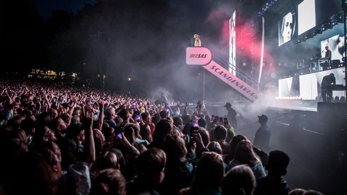 Karpe på scena under Øyafestivalen i 2019. Magdi står på toppen av ei flytrapp framfor eit folkehav.