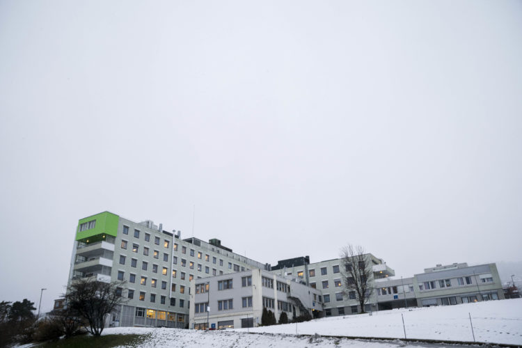 Hvit himmel øverst, og et hvitt sykehus nederst i bilder. Til venstre på sykehusveggen er det malt en limegrønn firkant. 