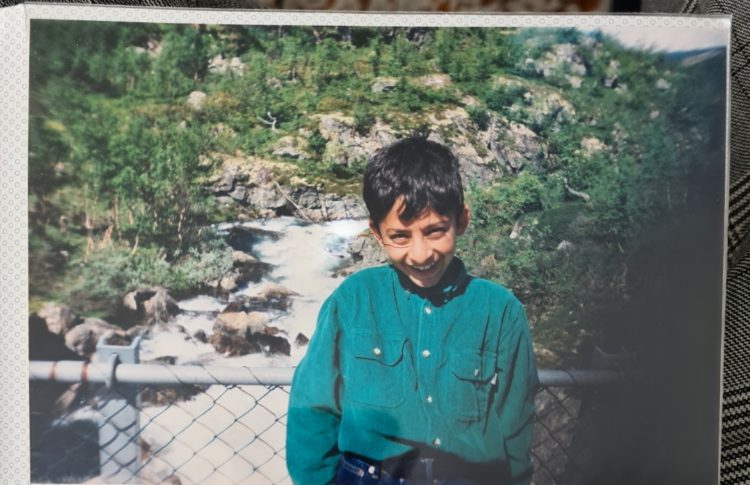 Bildet viser eit bilete i eit fotoalbum frå då Waleed var yngre. Han står framfor ein foss, og smilar beskjedent inn i kamera. 