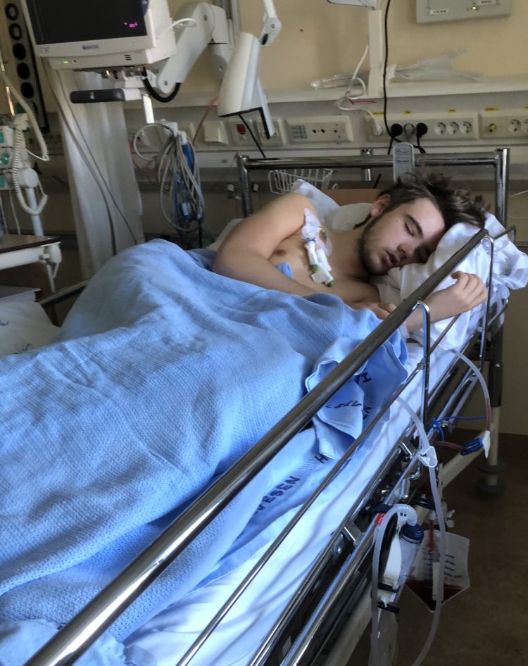 Marcus ligg i ei sjukehusseng og søv. Overkroppen er naken, og viser fleire slangar og elektrodar som er festa på brystet hans. 