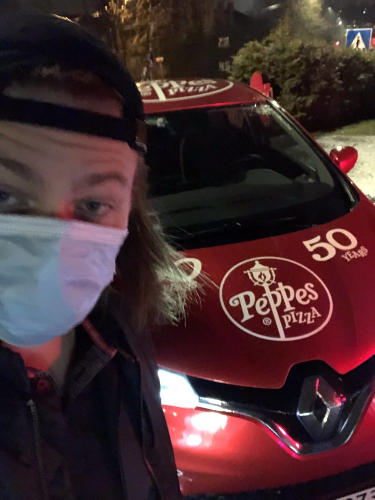 Ein litt uklar selfie av Markus som står med skuggelue og munnbind framfor ein Peppes pizza-bil. 