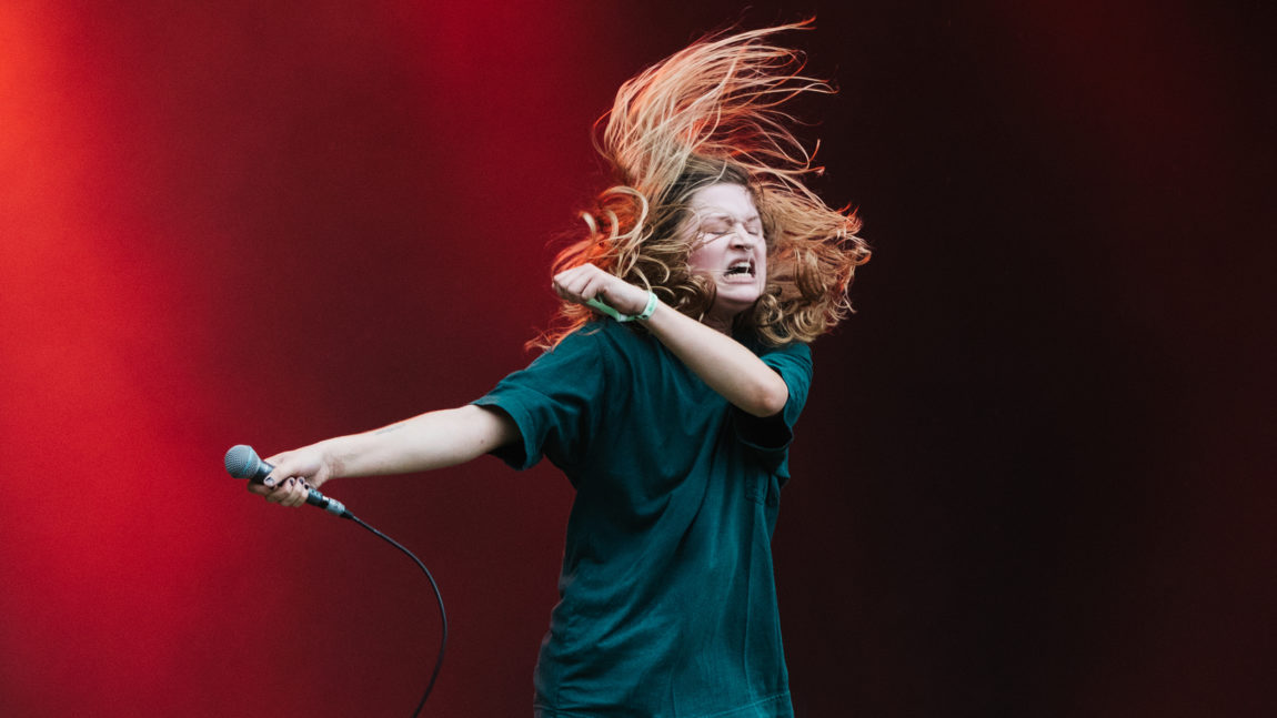 Et bilde av artisten Girl in red som kaster på håret på scenen og ser ut som hun er stappfull av energi