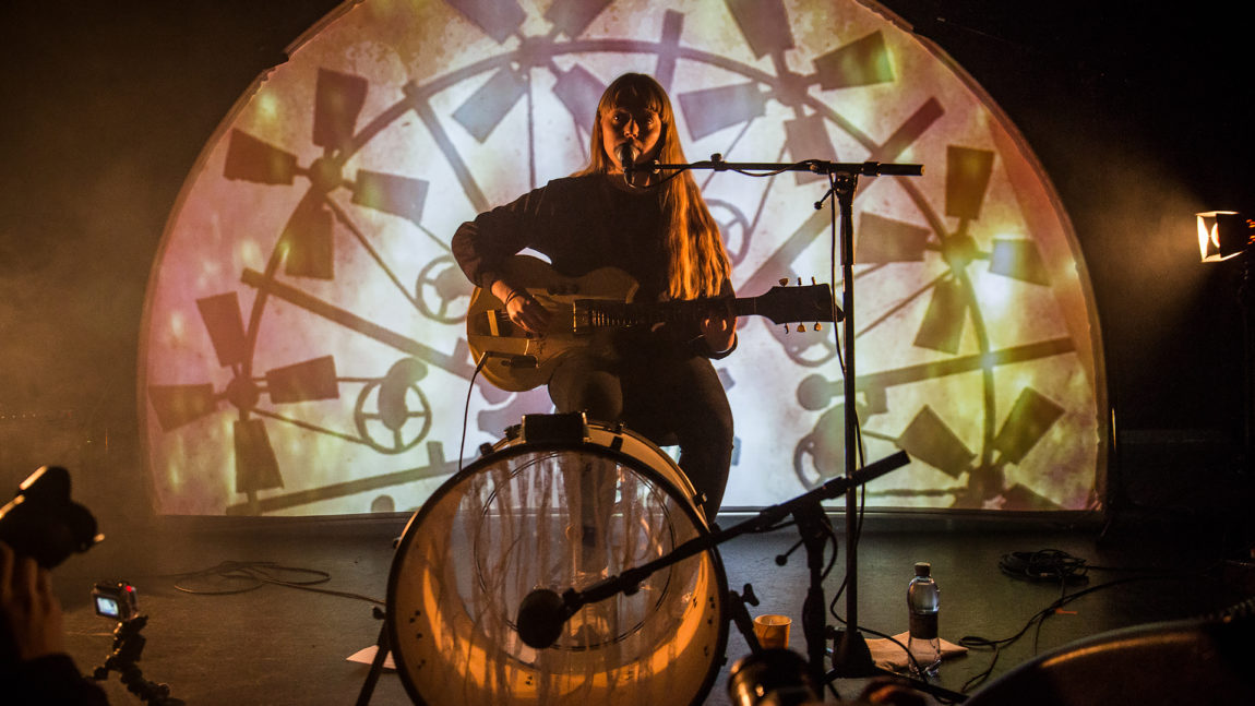 Et bilde av Vilde Tuv live alene på scenen med kun gitar, mikrofon og trommer