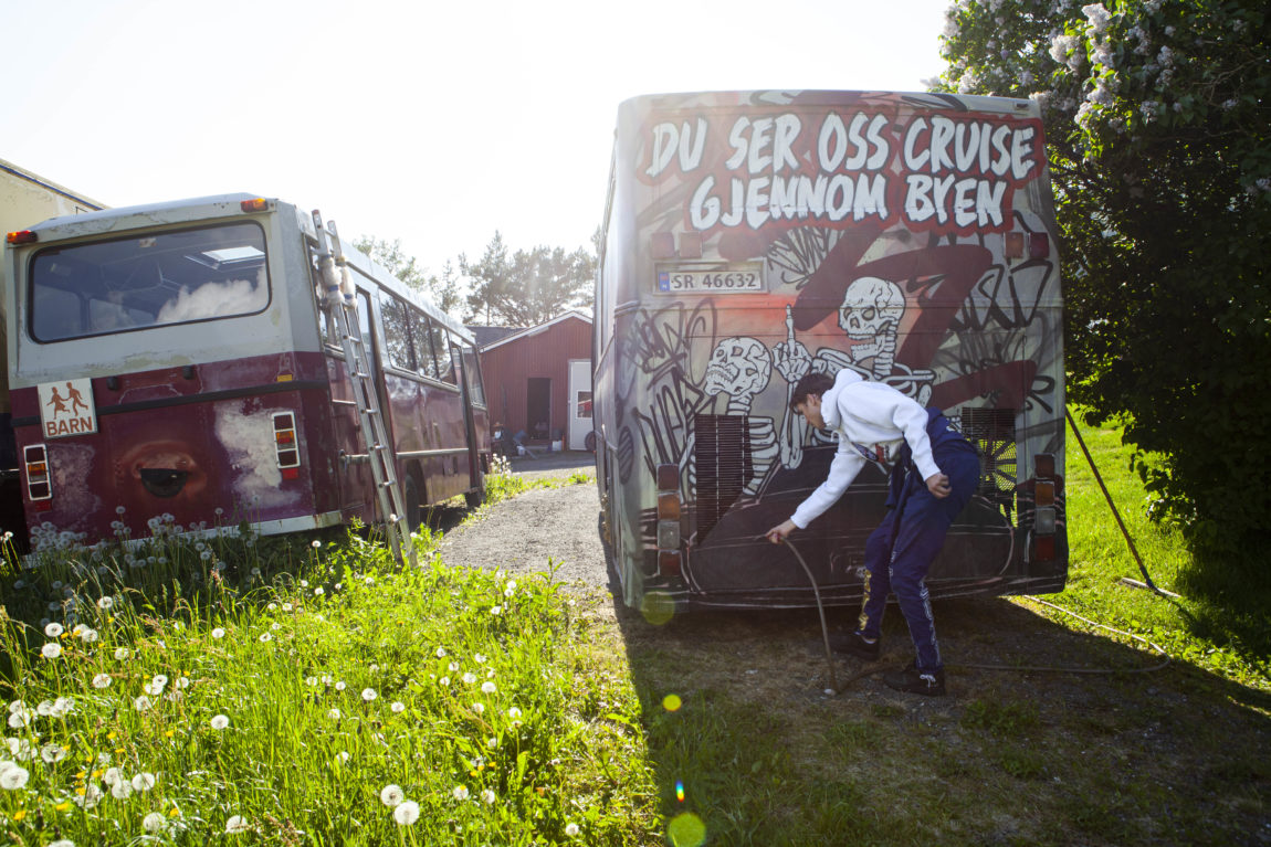 Jacob Lyche fiksar noko teknisk bak bussen. Bakpartiet er malt med grafitti.