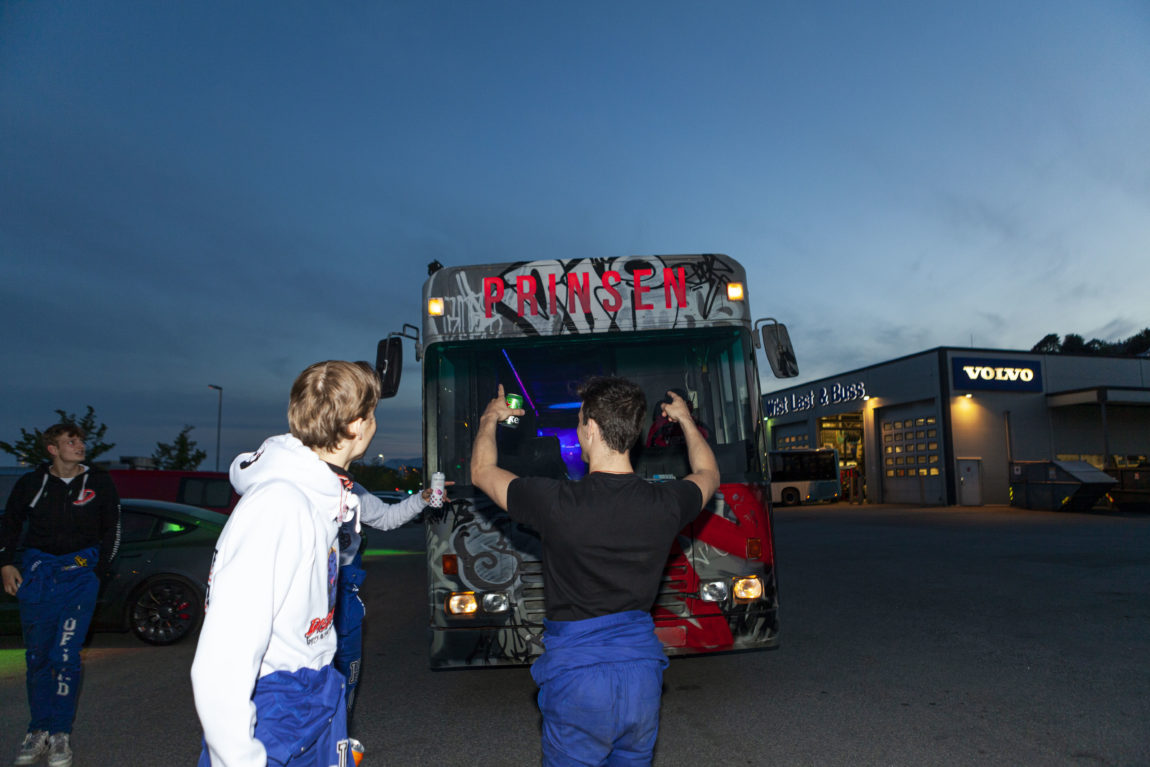 Gutane dansar og hoiar framfor den enorme leddbussen. Dei er klare for rulling. 