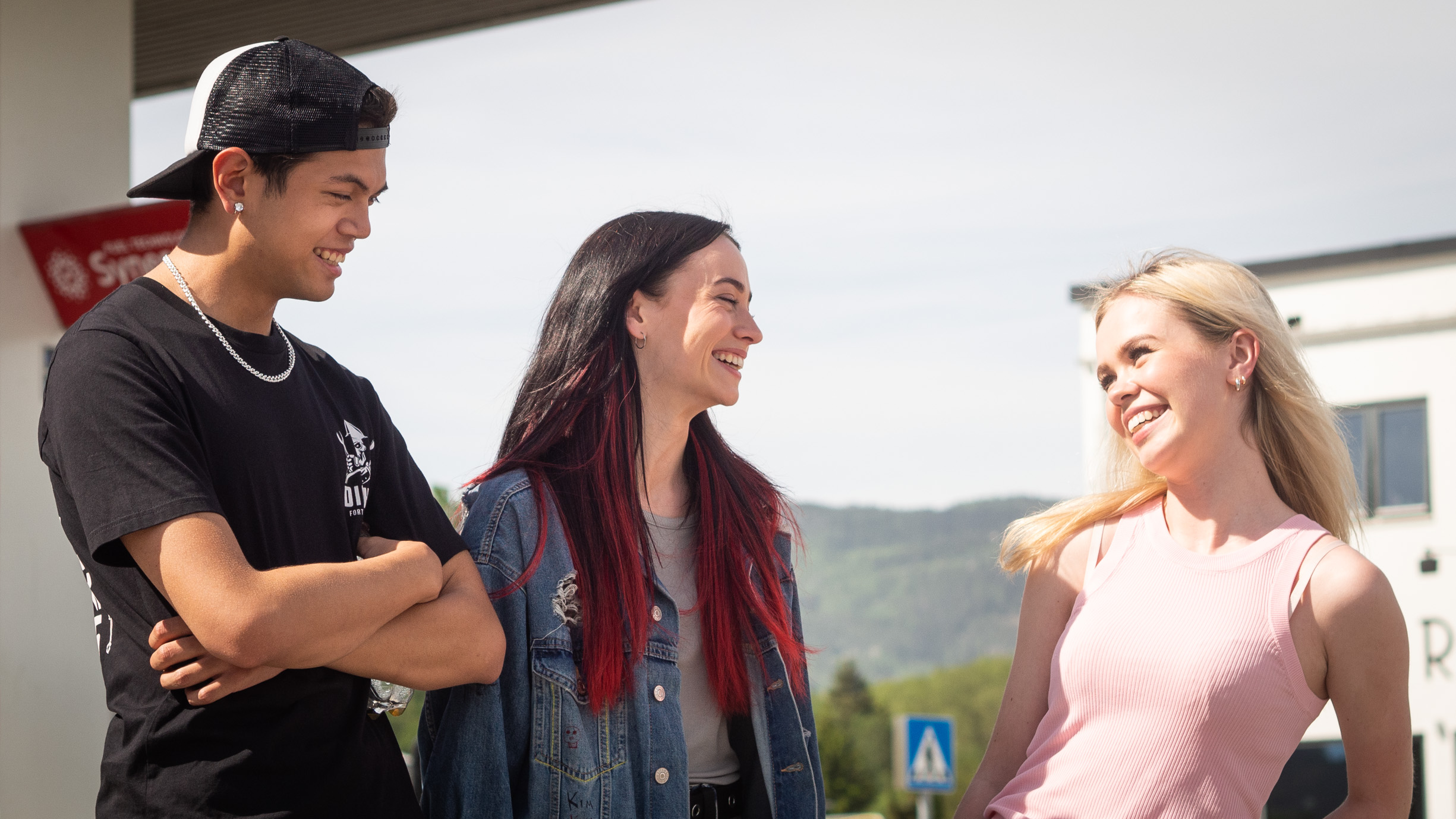 Et bilde av «Kim» (Matthew Santos) og Maja Christiansen (25), som spiller «Hege» i serien. De står på en bensinstasjon. De ser mot Amalie Sporsheim (20) spiller datteren til ordføreren, «Malene».