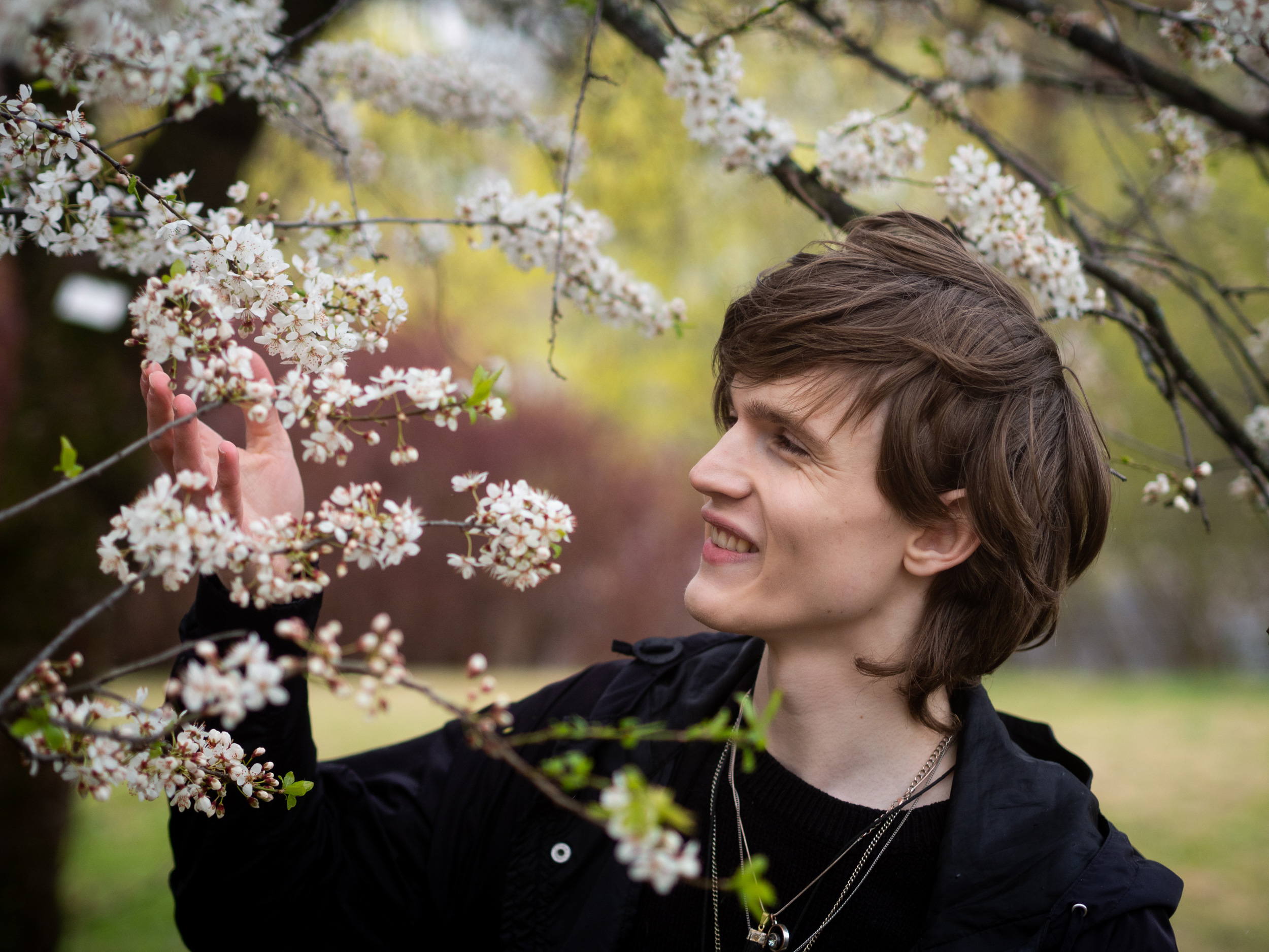 Et bilde av Simon som inspiserer blomstene på et tre i Botanisk hage på Tøyen mens han smiler