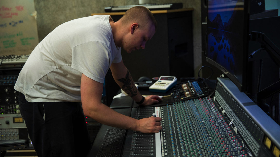Vokalist og lydteknikar i Lüt, Markus Danjord, står lent over eit miksebord i studio.