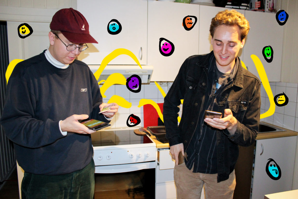 Sigurd og Nils står med mobil og bankkort i handa. Dei er konsentrerte medan dei prøver å bestilla bilett. Dei er på kjøkkenet sitt, med klassisk student-ikea-kjøkken i bakgrunnen.