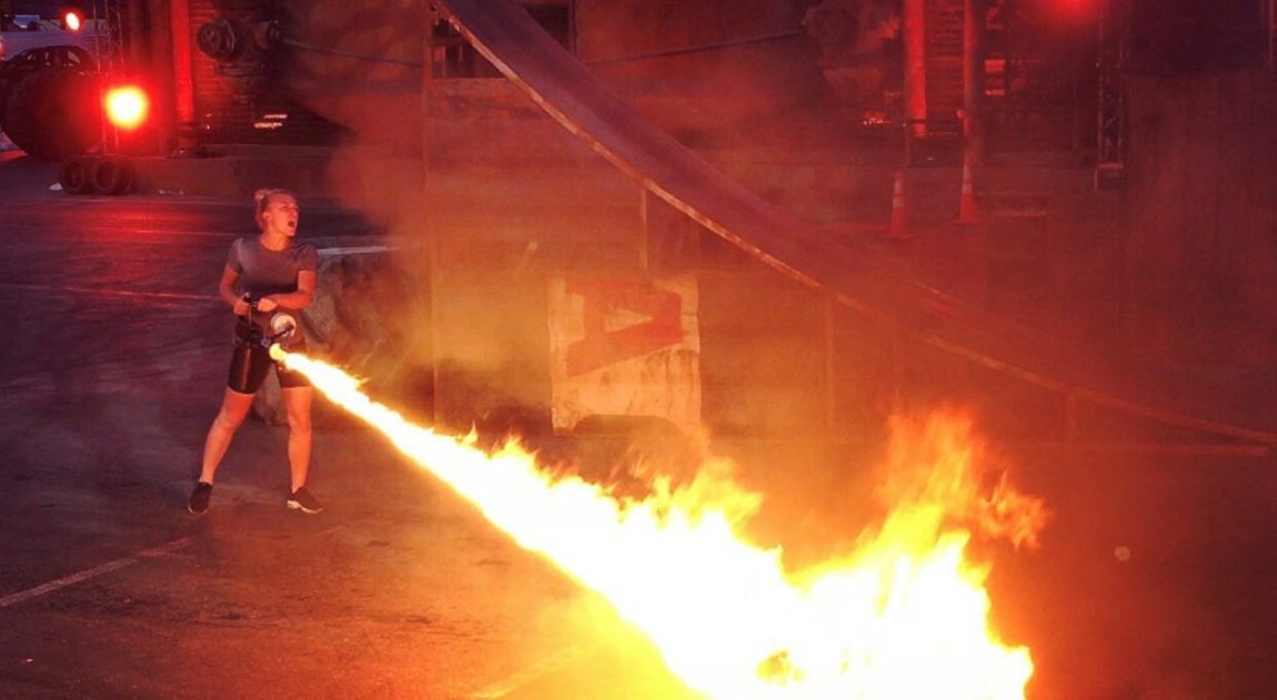 Bilde av Linn Solem som skyter flammer mot bakken. Det ser ut som hun holder en flammepistol, for det er hun som skyter flammene mot bakken..