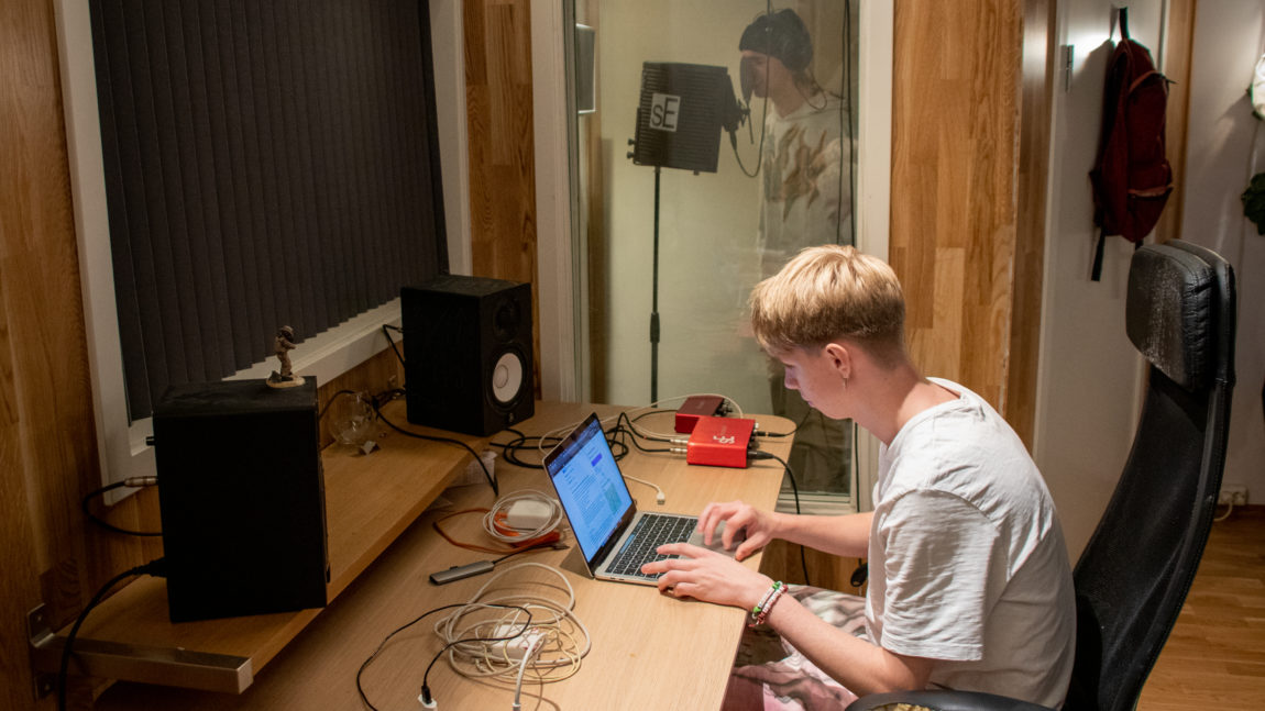 Bilde av Salomon som produserer musikk på macen deres. Emil er i studio og rapper.