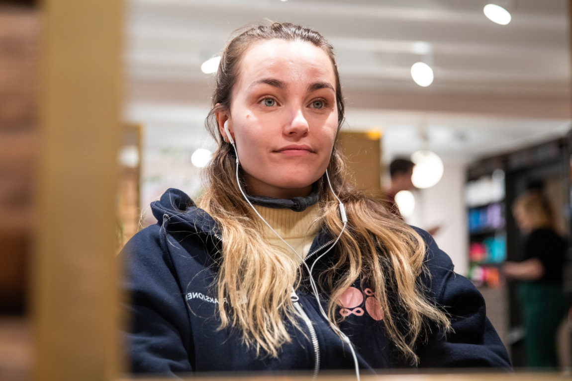 Adelina er litt stusselig stakkars. Hun venter på å bli gjort om til Rick. Hun har på seg en blå hettejakke, og har iphone-ørepropper.