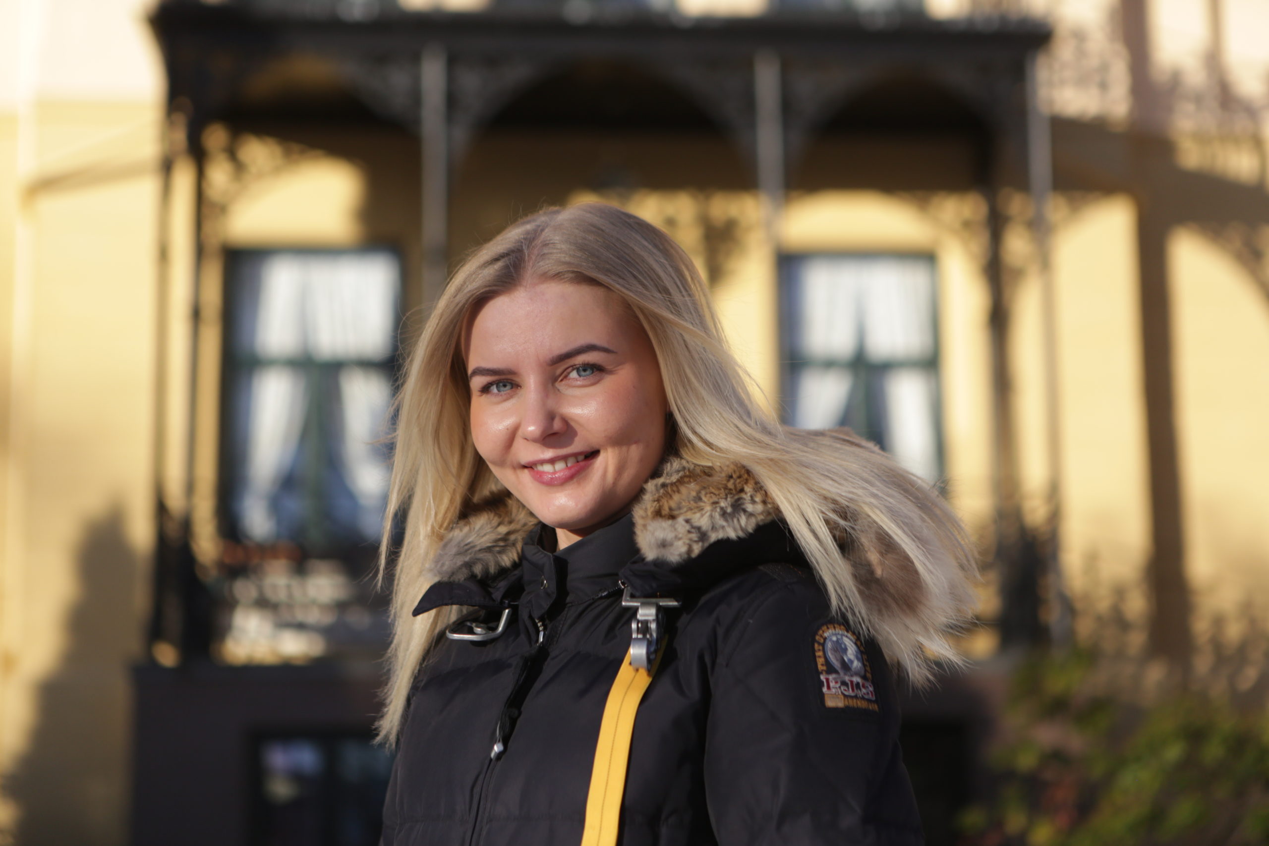 Bildet er av Selma Haugaas Alne (21). Hun har langt blondt hår og svart boblejakke. Hun smiler mot kameraet i kveldssolen.