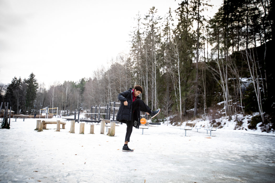 Makosir står trikser med en liten ball på en delvis snødekket lekeplass på Holmlia.