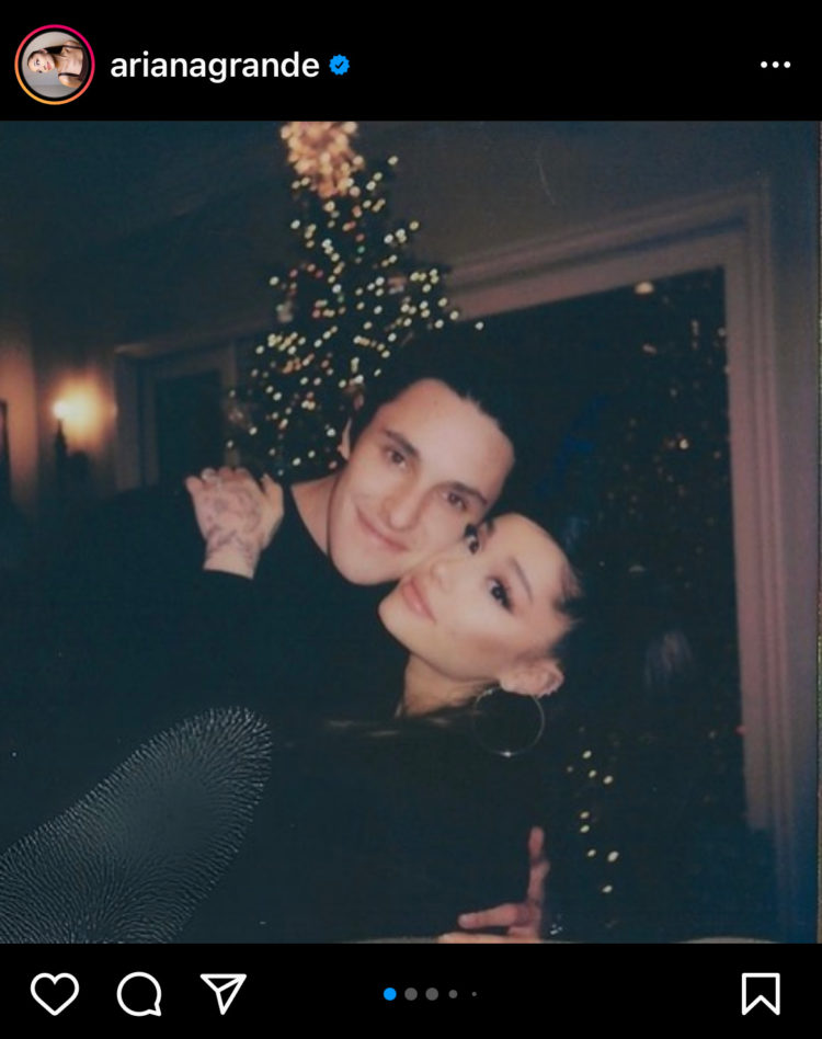 Et bilde fra Ariana Grandes Instagram. Hun står foran juletreet sammen med Dalton. De holder rundt hverandre og er kinn mot kinn. e har begge på sorte antrekk og har sort hår.