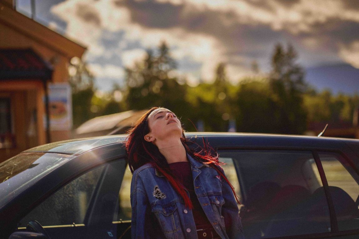 Ved solnedgang, ute i norsk natur ved Bø, lener skuespilleren Maja seg lang tilbake på bilen. Du ser at hun er veldig sliten etter en lang dag. 