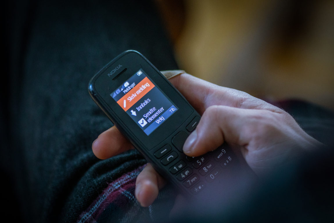 I bildet lyser den svarte Nokiaen til Even opp. Han holder den med en hånd og trykker seg inn med midttasten for å skrive en ny melding. Feltet for nye meldinger lyser opp i oransje toner. 