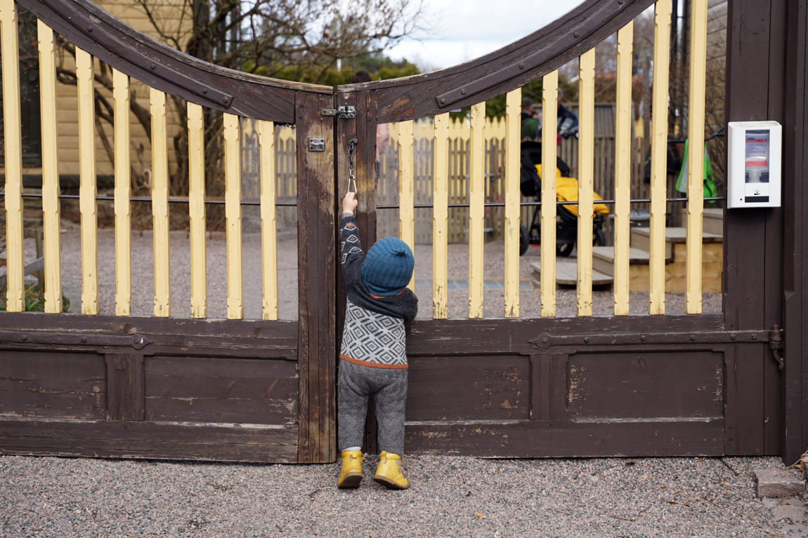 Matheus står på tærne i et forsøk på å lukke den gule porten etter seg. Den lille kroppen er altfor lav til å nå opp til låsen. 
