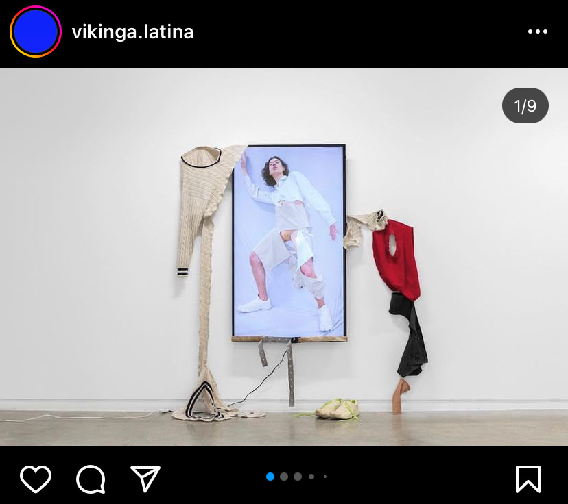 Skjermbildet fra Intis instagramprofil viser kunstverket hans slik det opprinnelig så ut i 2019. en skjerm henger på høykant på den hvite veggen. I hjørnene av den henger oppstykkede klesplagg. På skjermen vises et selvportretter av Inti med hvite opprevne klær på.