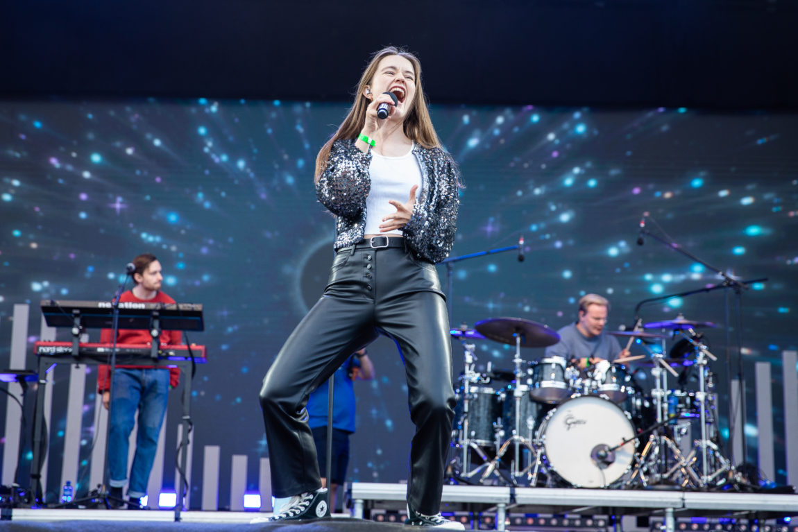 Sigrid står på scenen og skriker i mikrofonen. Hun har på seg en blinkende diamantjakke. Og langt flagrende brunt hår. Vi ser hele beinene hennes.