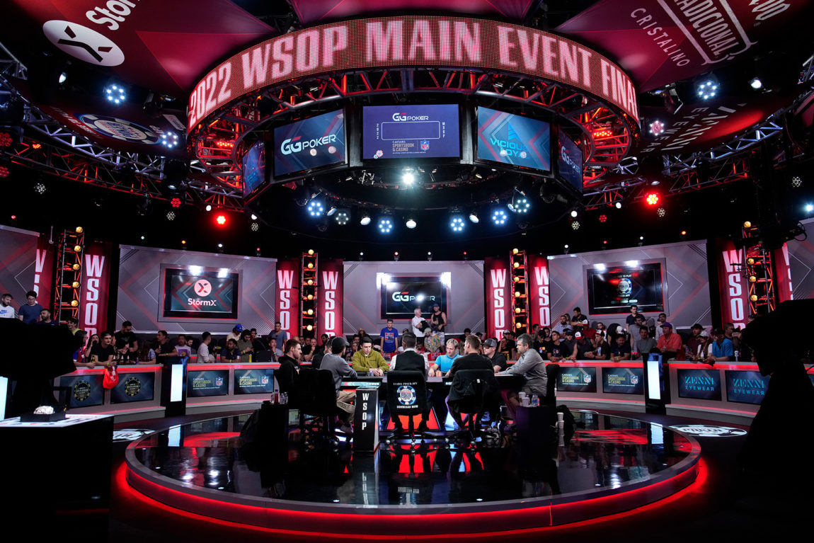 Bilde fra siste runde i i World Series of Poker i Las Vegas fra 2022. Bordet står på en rund oppheving fra bakken, og rundt dem står publikum. Det er flere røde lys rundt i lokalet og mange skjermer overalt med ulik reklame på. 