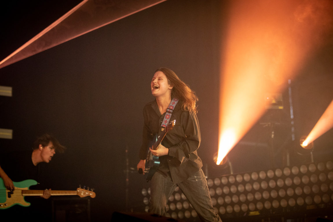 Girl in red smiler, mens hun løper og spiller gitar samtidig.