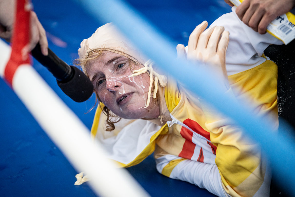 Anna Nor Sørensen har Majones over hele ansiktet. Hun ligger mørbanket på brytematten med en gul drakt.