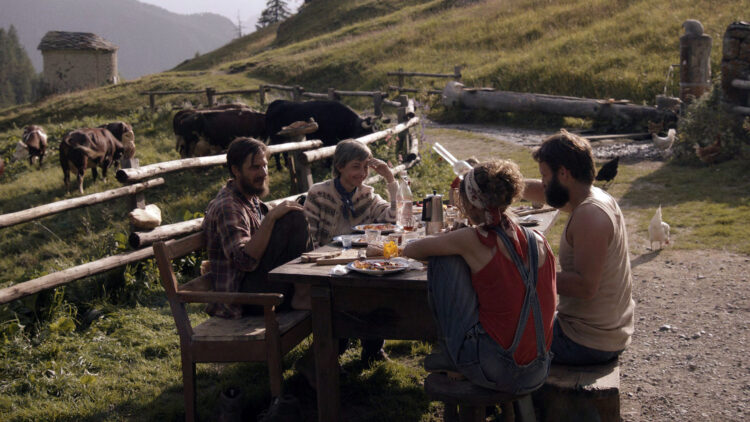 Bruno (Alessandro Borghi) og Pietro (Luca Marinelli) sitter utenfor hytta si sammen med to damer i filmen «De åtte fjellene».