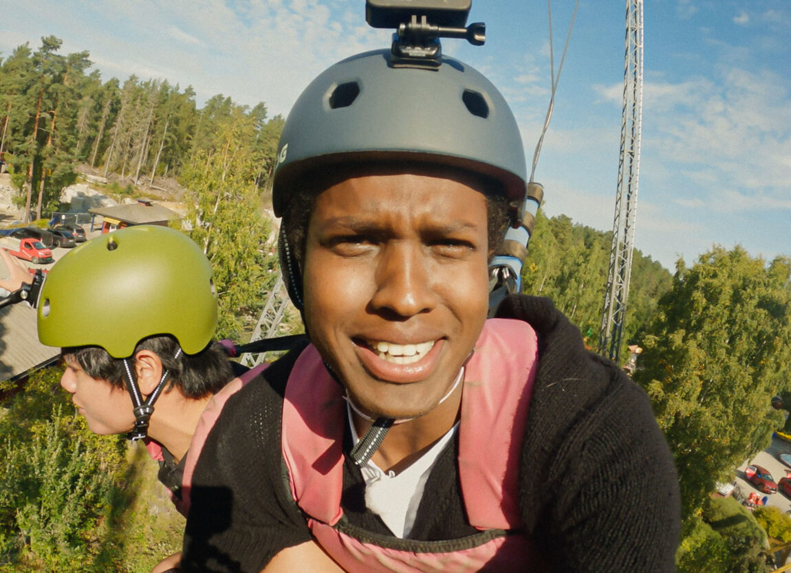 Magan Gallery (28) henger i løse lufta fra skycoasteren på tusenfryd. Han smiler skremt i kamera, har på seg en blå hjelm, en rød redningsvest og en svart genser.