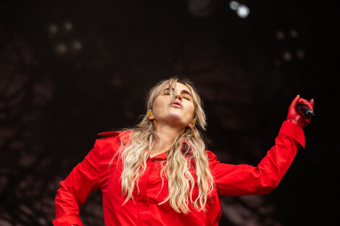 Ingrid Helene Håvik har langt hår og rød buksedress. Hun danser løs og peker venstre hånden oppover.