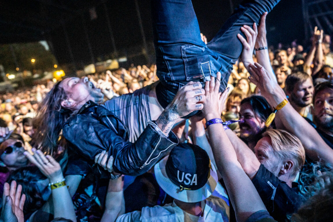 Vokalisten i Kvelertak har på seg trange jeans og skinnjakke. Han ligger midt i publikum og crowdsurfer. Hans fans holder ham oppe med hendene mens de smiler og ler.