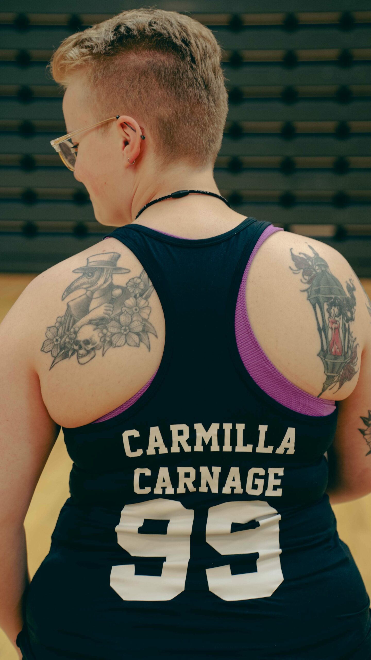 Eivor står med ryggen til kamera, og singleten hennes er i fokus. På den står spillernavnet "Carmilla Carnage" og spillenummer 99. På begge skulderbladene har hun to store tatoveringer.