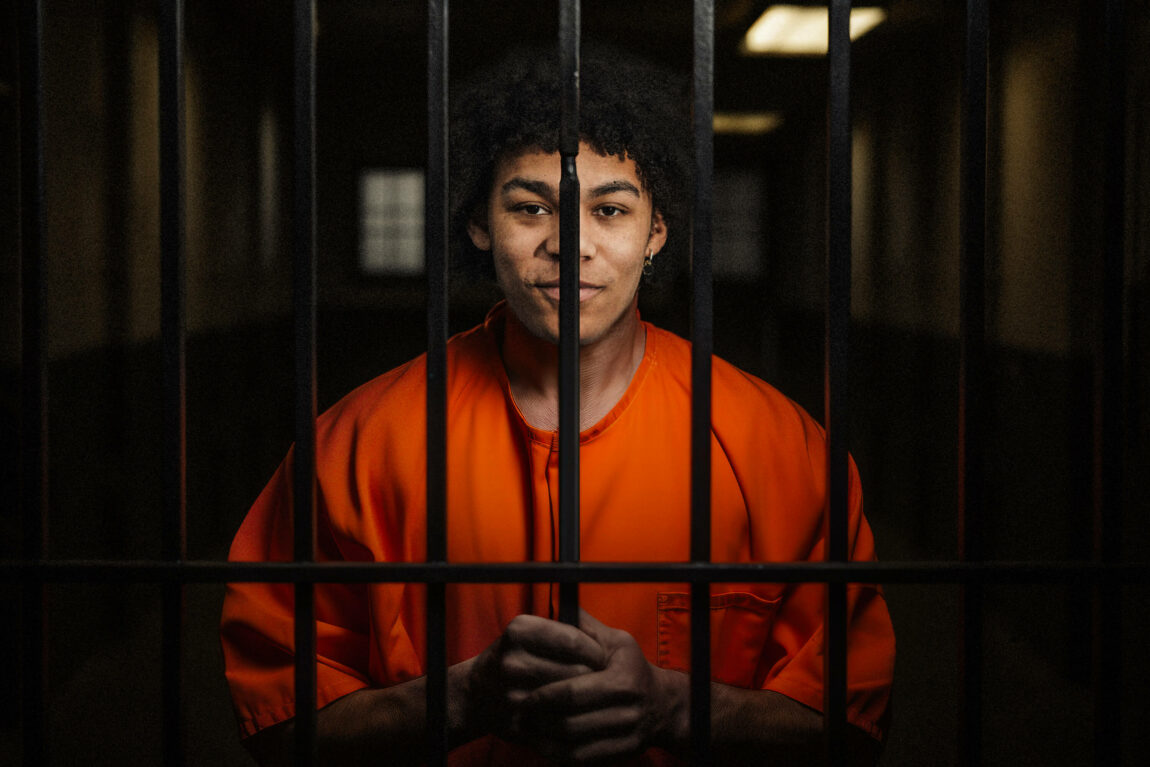 Ai-generert og photoshoppet bilde av Bargee bak lås og slå. Han har en oransj fangedrakt på seg, og står bak gitteret i et fiktivt fengsel. 
