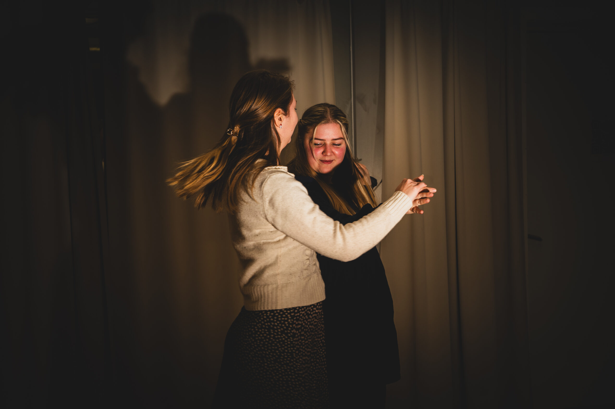 Birgit og Ranveig danser i dunkel belysning, i gardinene i dansesalen reflekteres skyggene deres.