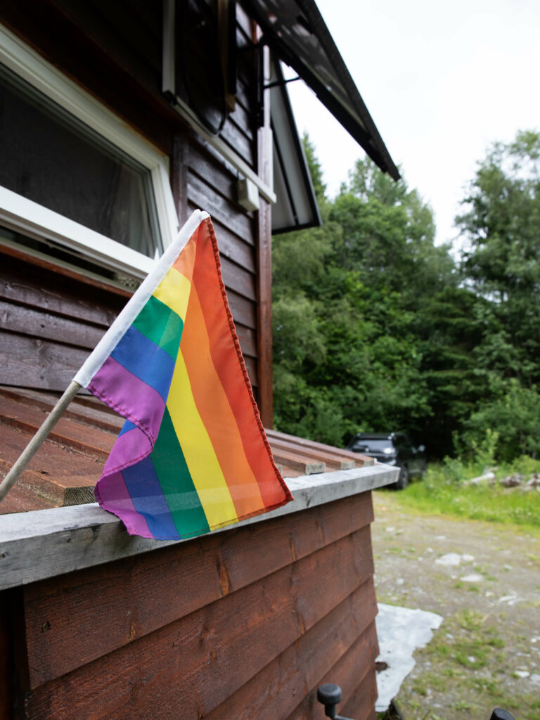 Eit prideflagg som er festa på utsida av minihuset flagrar i vinden