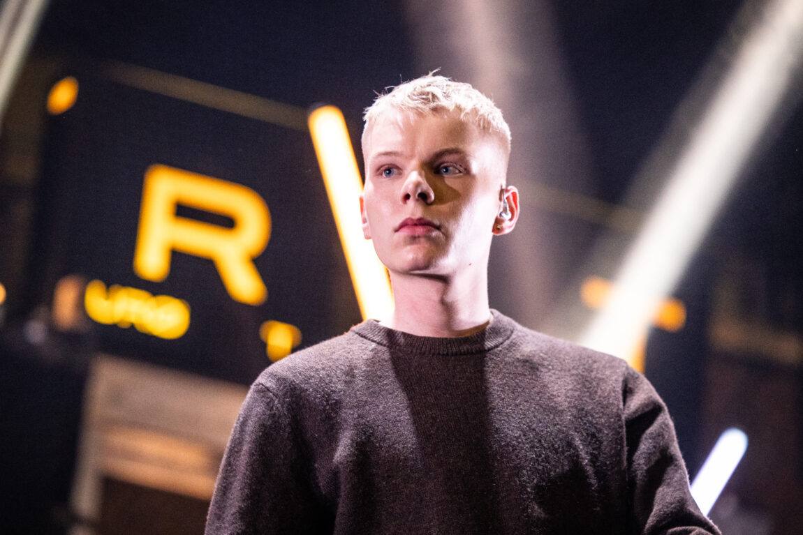 Anakin Justin har på seg en brun genser og rapper og hoier